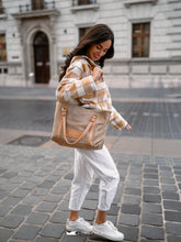 Kép betöltése a galériamegjelenítőbe: Femeie care ține o geantă shopper bej pe o stradă din oraș.