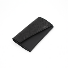 Kép betöltése a galériamegjelenítőbe: A black leather wallet with a textured pattern, closed with a magnetic snap.