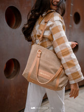 Încărcați imaginea în vizualizatorul Galeriei, Persoană care poartă o geanta bej cu bretele maro, pe fundal cu perete texturat.

