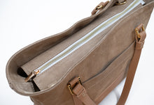 Încărcați imaginea în vizualizatorul Galeriei, Prim-plan cu o geantă bej cu fermoar auriu pe fundal alb.

